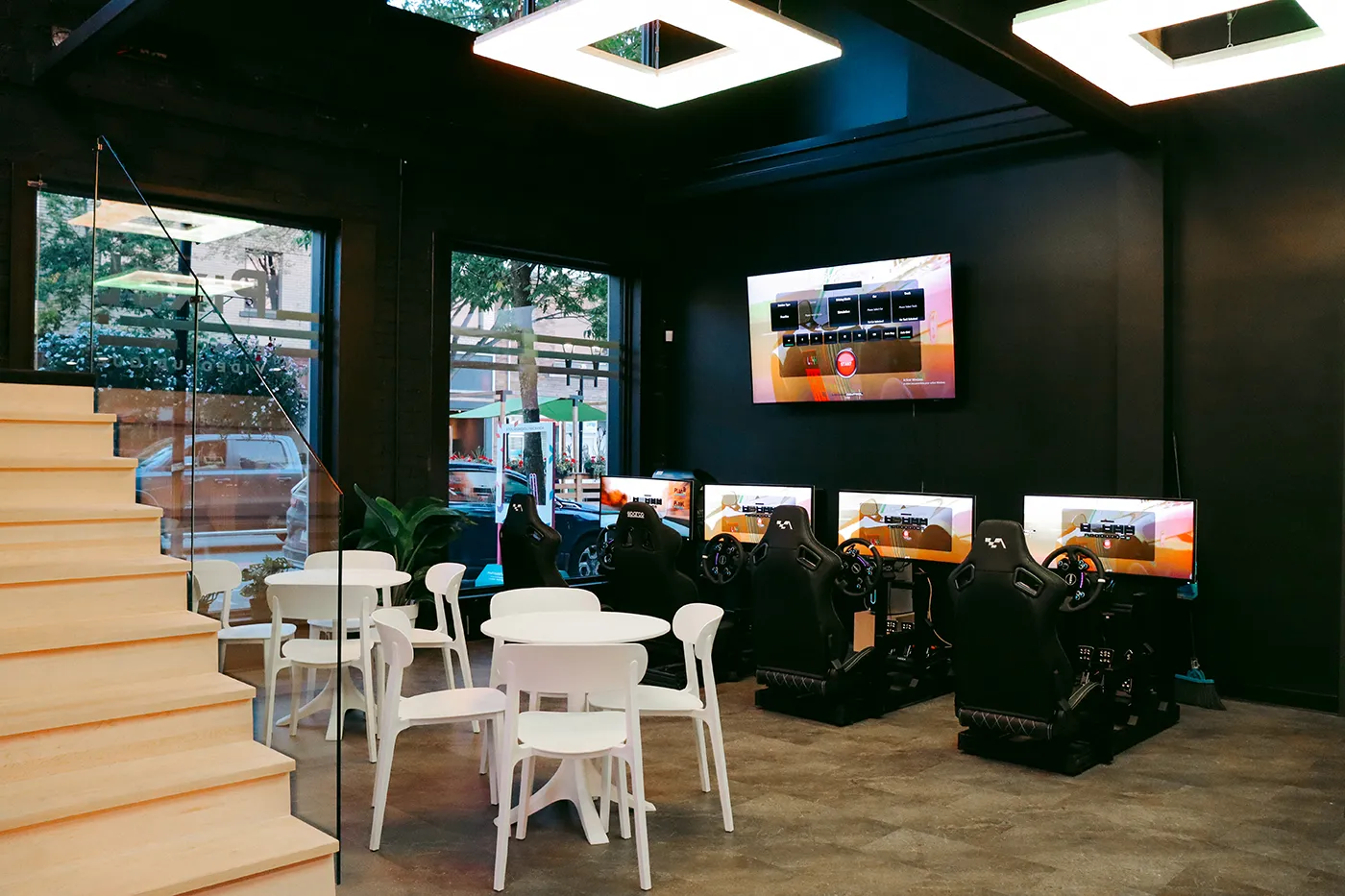 La salle du Pixel : simulateurs de course, tables, escalier et grandes fenêtres sur l'avenue Principale